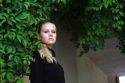 Young woman standing against plants