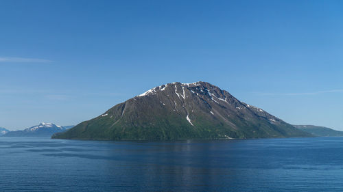 Scenic view of sea and mountains against blue sky