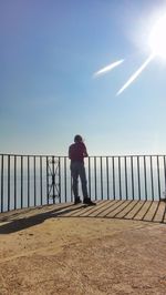 Rear view of man standing on sea against clear sky