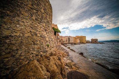 Sea by buildings against sky