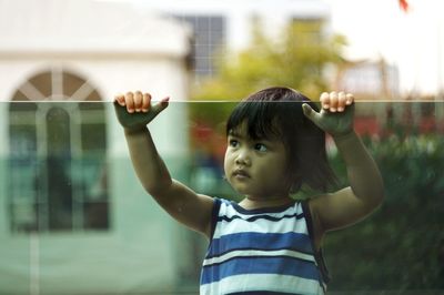 Close-up of cute boy standing against building