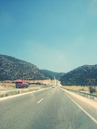 Road leading towards mountains against blue sky