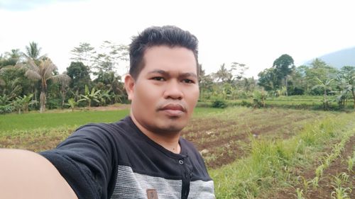 Portrait of young man on field against sky