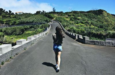 Rear view of woman on road against sky