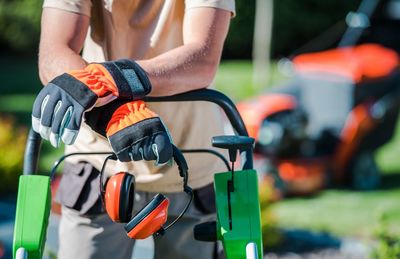 Midsection of man with gardening equipment standing in garden