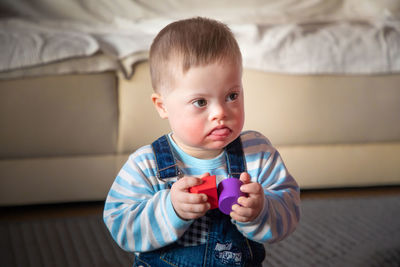 Baby boy playing with toy blocks while sitting at home