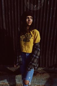 Portrait of smiling woman standing against wall