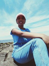 Portrait of smiling young woman sitting against sky