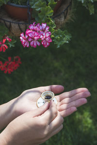 Close-up of hands holding tiny cup and saucer