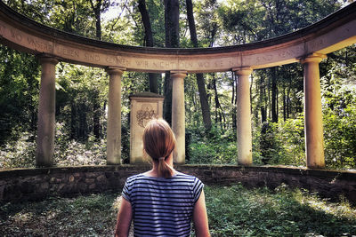 Rear view of woman standing against trees