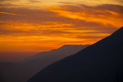 Scenic view of silhouette mountains against orange sky