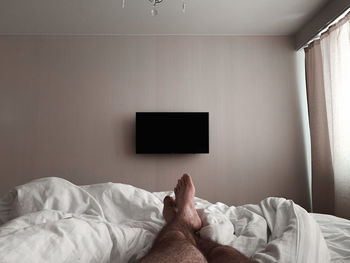 Low section of person relaxing on bed at home