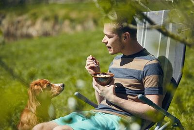 Young man with dog sitting outdoors