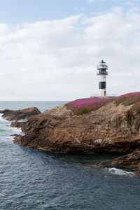 Lighthouse by sea against sky