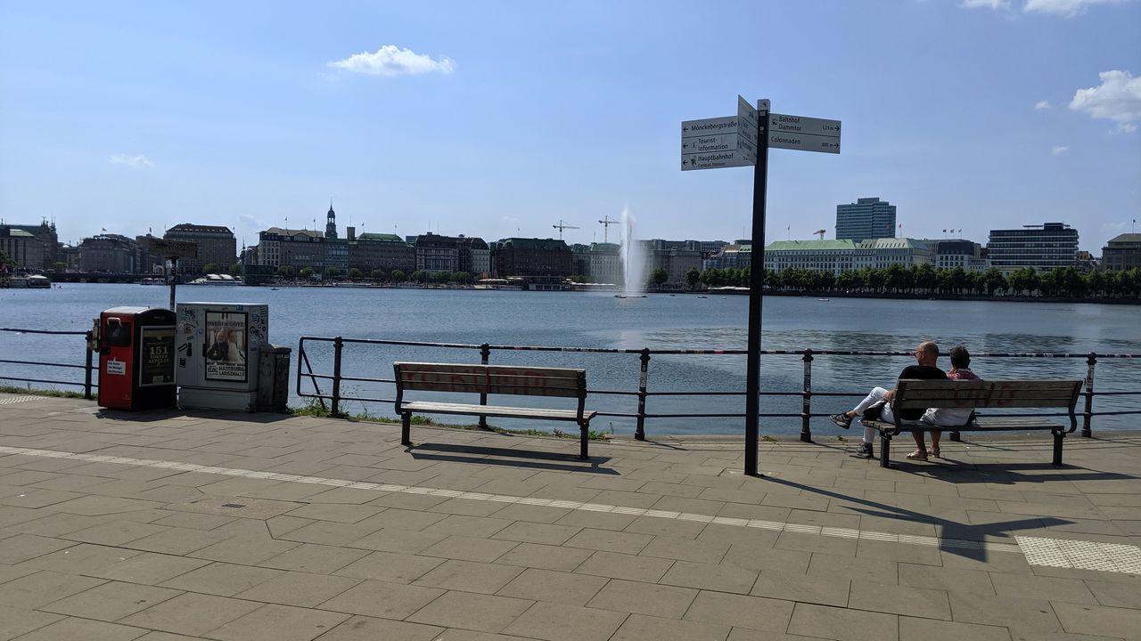 REAR VIEW OF MAN SITTING ON BENCH IN RIVER