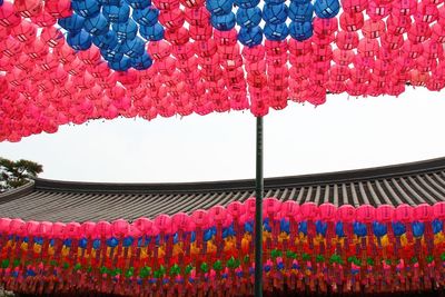 Multi colored lanterns hanging on wall against clear sky