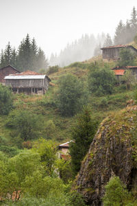 House on field by trees and houses against sky