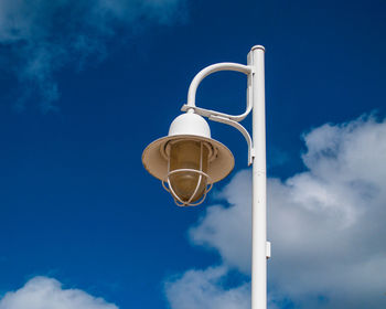 Low angle view of electric lamp against blue sky