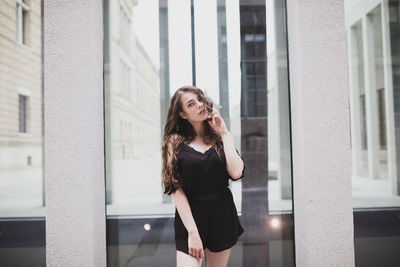 Portrait of young woman standing against building