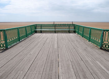 View of wooden pier leading towards sea against sky