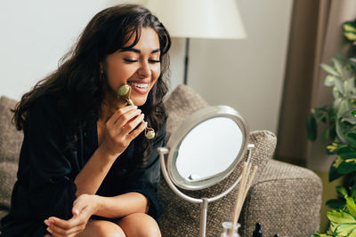 Smiling woman looking at mirror at home