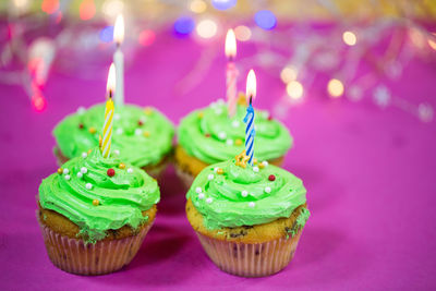 Close-up of cupcakes with burning candles on table