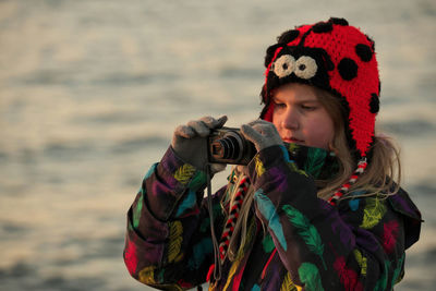 A 9 year old girl practices her photography and camera skills at the beach in the evening