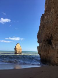 Rock formation on beach against sky