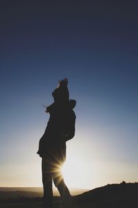 Silhouette woman walking on field against sky during sunset