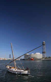 Sailboat sailing in sea against clear blue sky