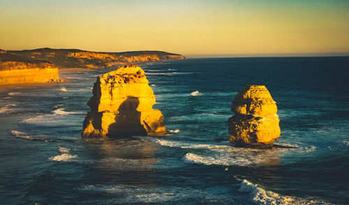 Scenic view of rock formation in sea against sky during sunset