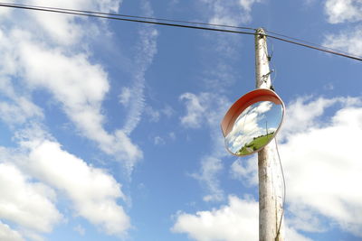 Low angle view of mirror on telegraph pole against sky