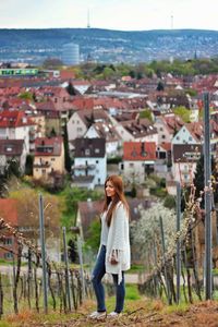 Full length side view of woman standing at farm against cityscape