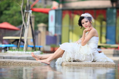 Young woman sitting on stone in water