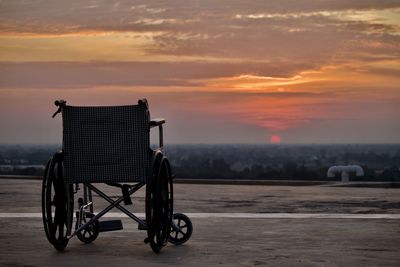 An empty wheelchair on the deck as the sun sets.