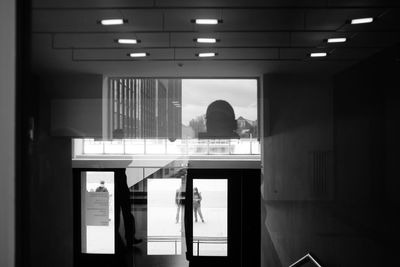 Rear view of woman standing in illuminated building