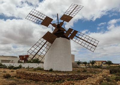 Traditional windmill on landscape against sky