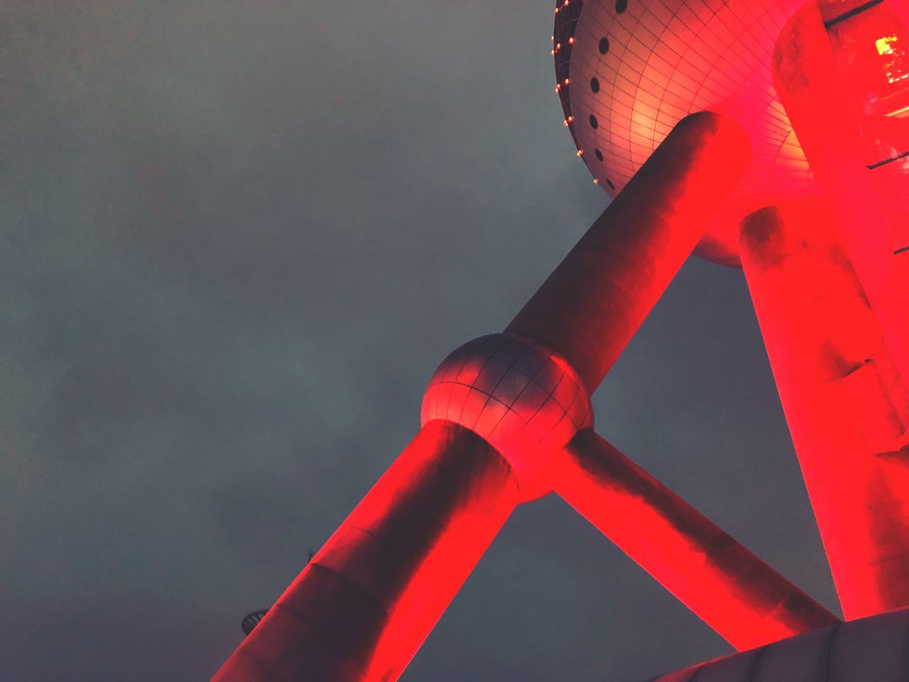 LOW ANGLE VIEW OF ILLUMINATED RED LIGHT AGAINST SKY