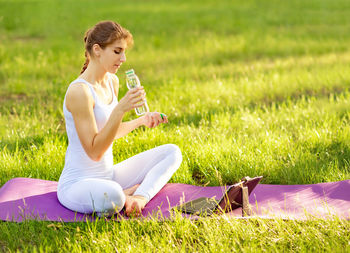 Woman drinking water while exercising in park