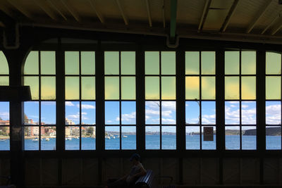 Man sitting on bench by glass window