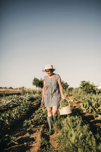Female worker holding basket while walking at agricultural field