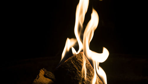 Close-up of burning candle against black background