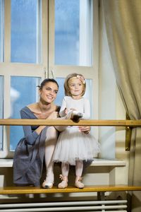 A little ballerina ties pointe shoes to an adult ballerina.