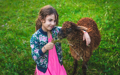 Happy girl feeding grass to sheep