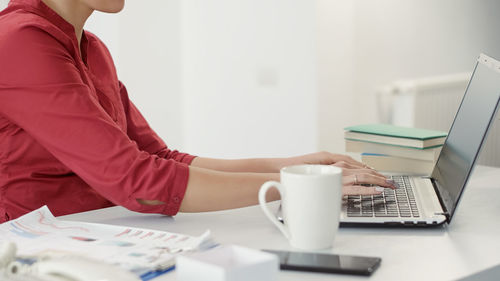 Midsection of woman using laptop on table