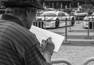 Man drawing car sketch in city