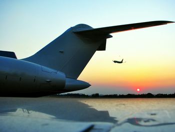 Airplane flying in sky at sunset