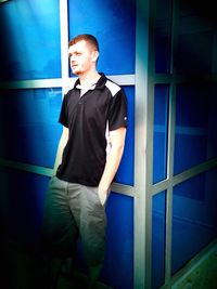 Portrait of man standing against blue wall