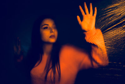 Close-up of teenage girl seen through plastic looking away while standing against wall