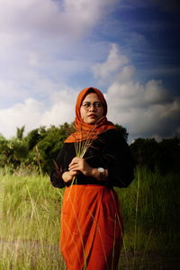 Portrait of young woman standing on land against sky